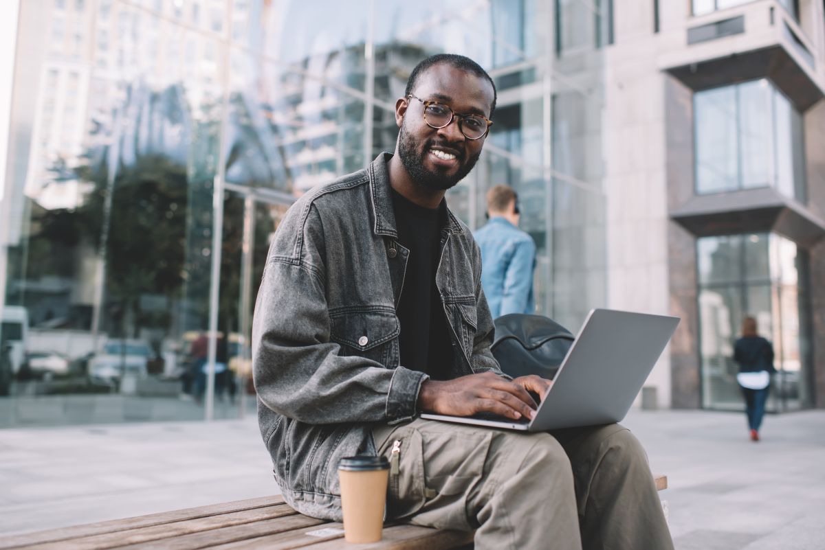 Portrait d'un freelance souriant à la caméra pendant le temps de travail à distance sur ordinateur