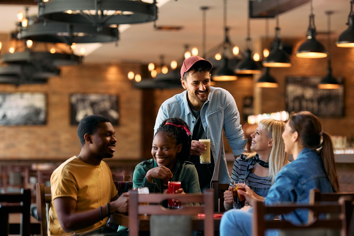 Groupe d'amis heureux discutant en se réunissant dans un pub.