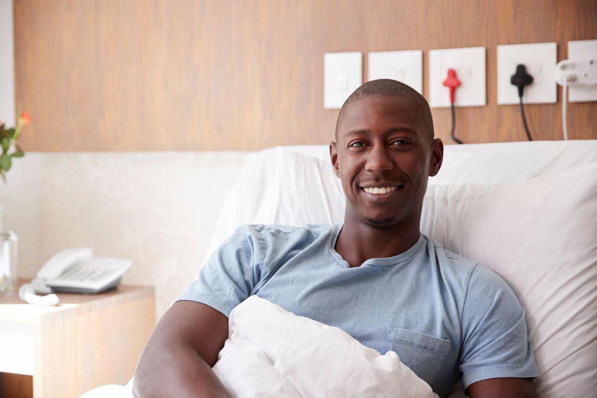 Portrait d'un patient de sexe masculin allongé dans un lit d'hôpital souriant à la caméra