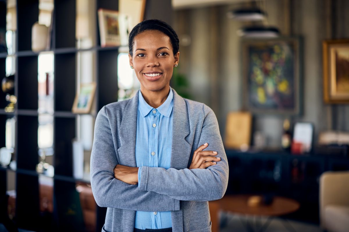 Portrait d'une femme souriante, les mains croisées au bureau.