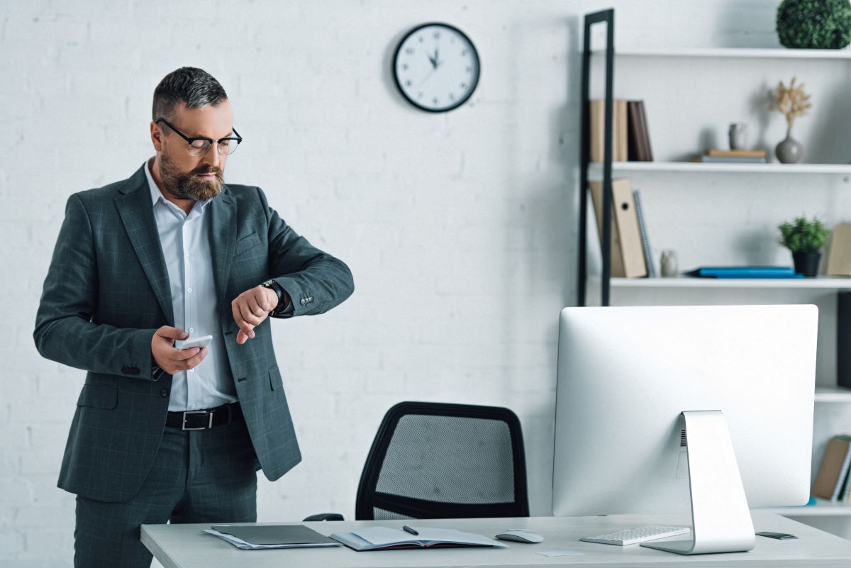 Un freelance au bureau regarde l'heure